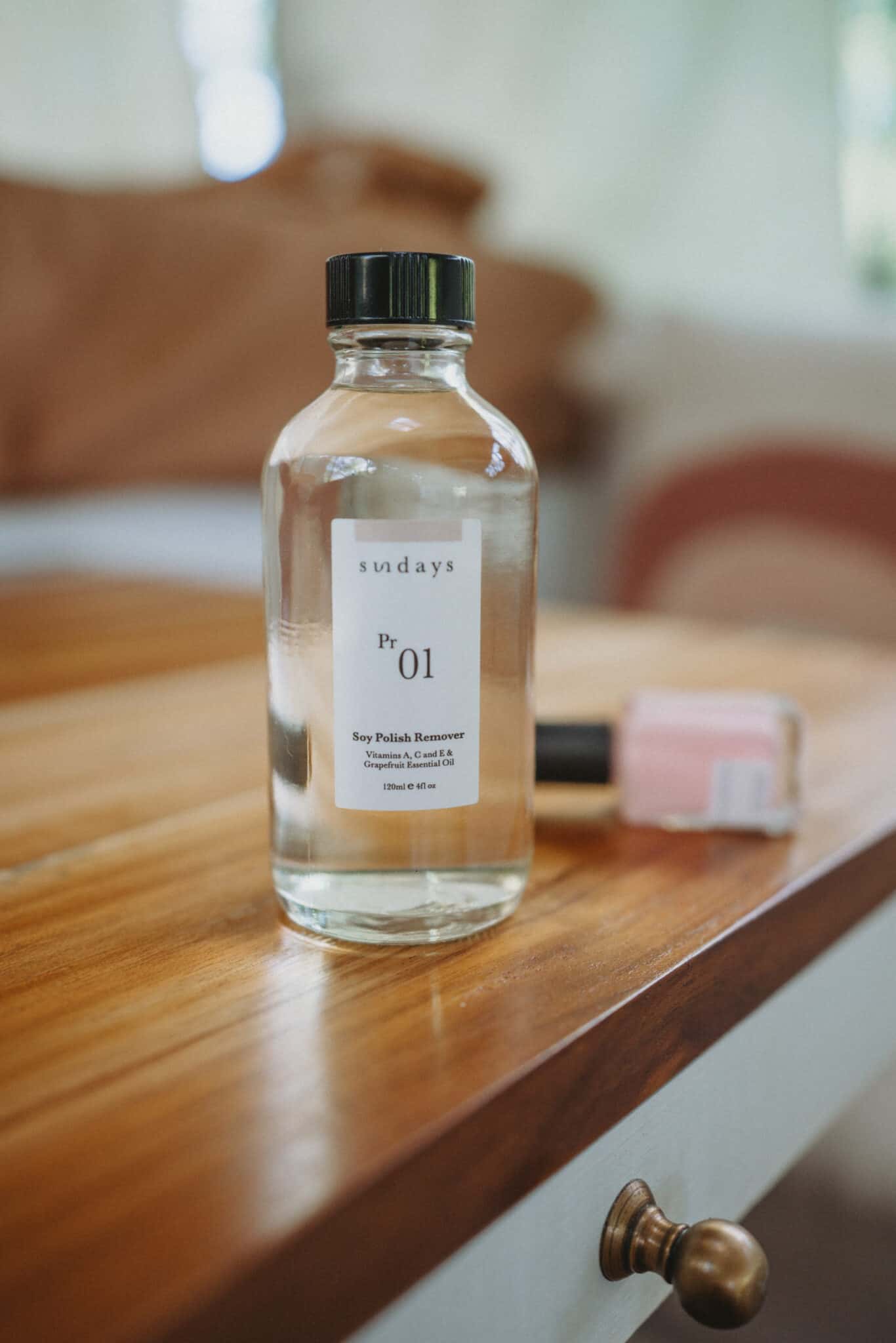 A plastic-free bottle of nail polish on a wooden table.