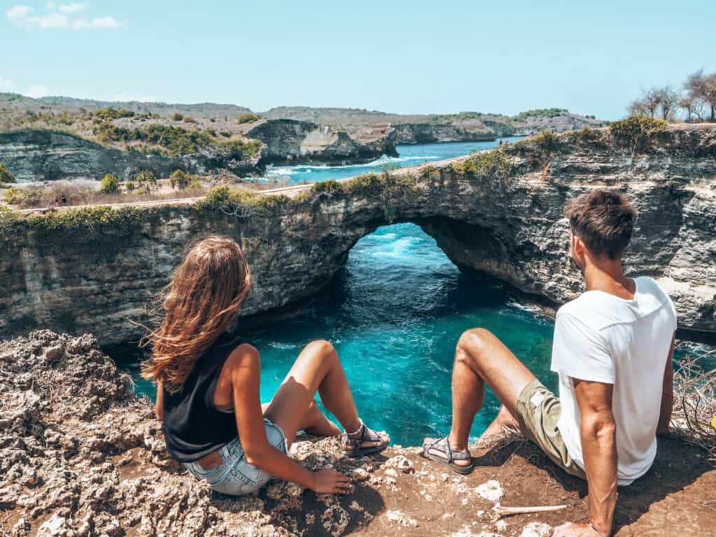 Couple sitting on the cliff of Broken Beach Nusa Penida