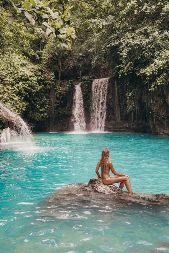 Women sitting on rock at kawasan falls Cebu Level two