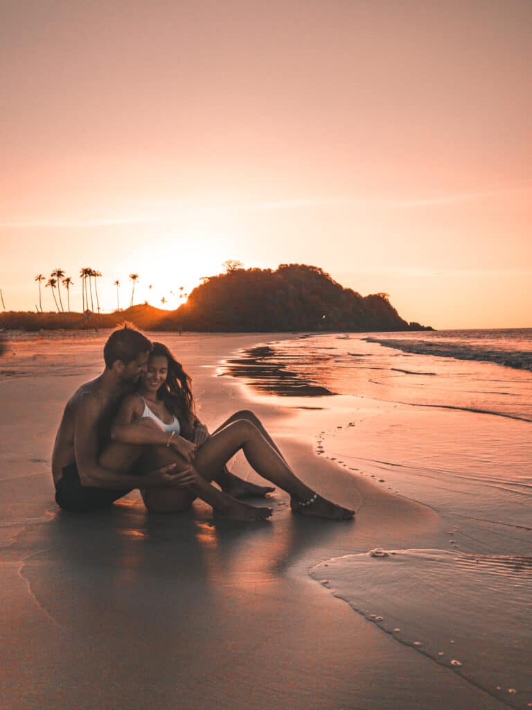 Couple sitting at Nacpan Beach on Sunset El Nido Philippines
