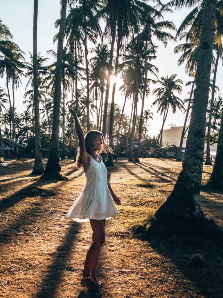 Women dancing in palm tree forest at sunset at Nacpan Beach El Nido Philippines