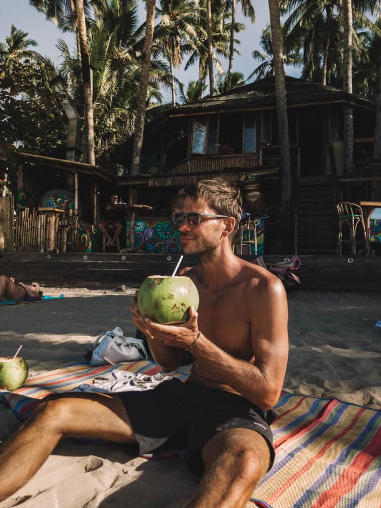 Man drinking coconut at Nacpan Beach El Nido Philippines