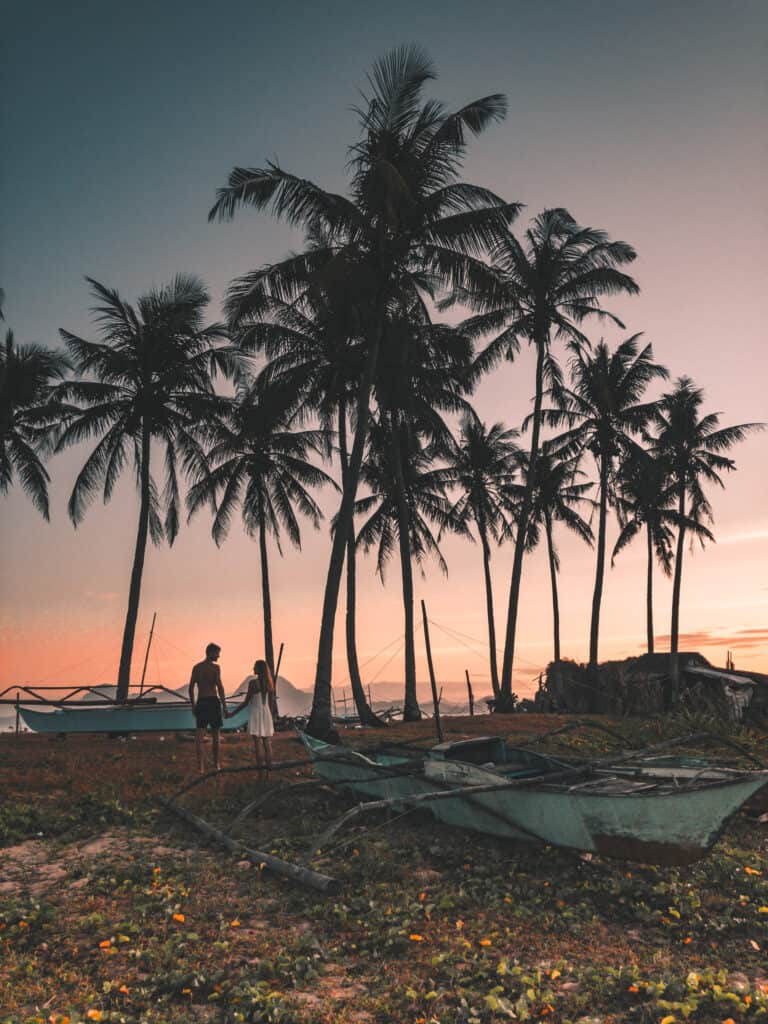 Couple at Nacpan Beach on Sunset in front of palm trees