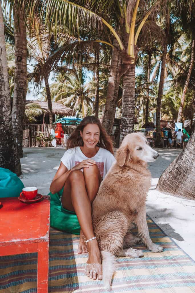 Women sitting with a dog on the beach at Cloud 9 in Siargao