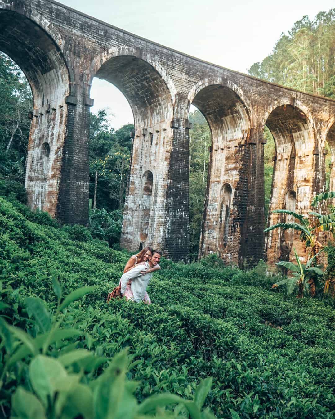 Couple in tea field in front of nine arches bridge ella