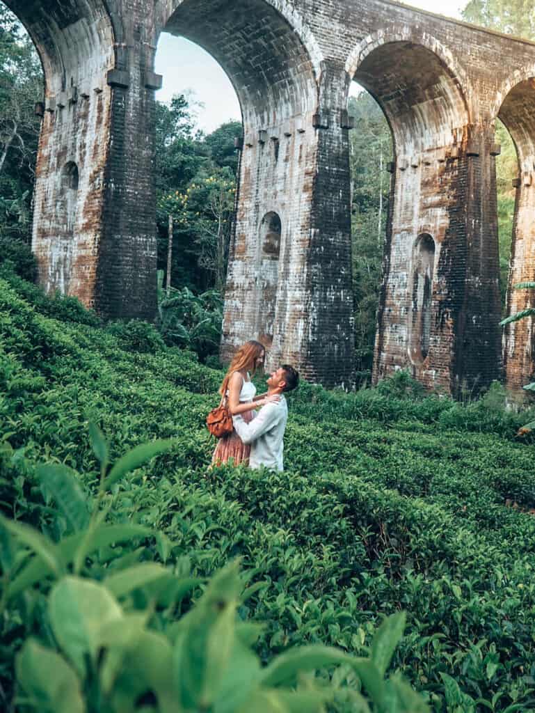 Couple in tea field in front of nine arches bridge ella