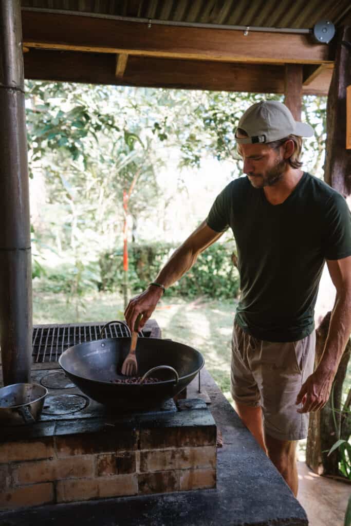 Man is roasting cacao beans over wood fire at La Amistad Chocolate farm