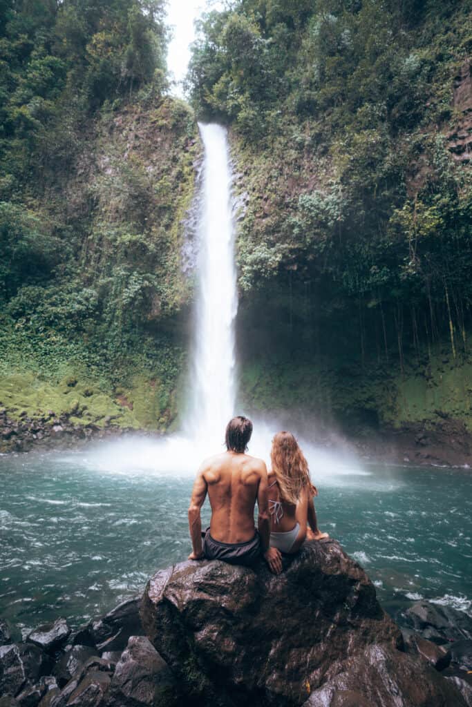 Couple sitting on a rock at La Fortuna Waterfall Costa Rica