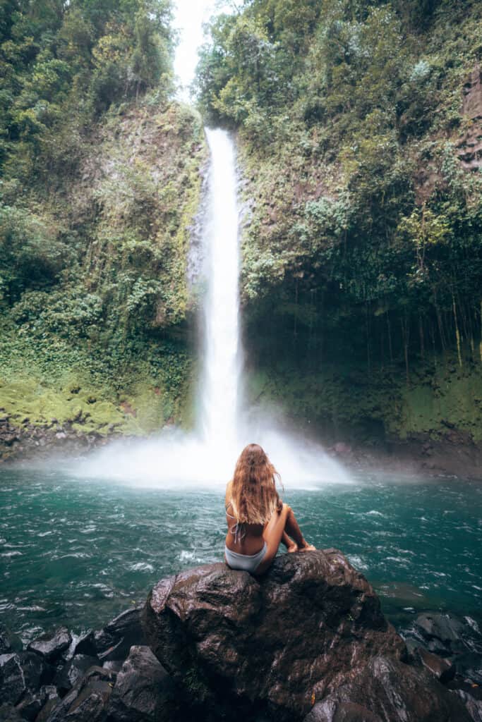 Woman sitting on a rock at La Fortuna Waterfall