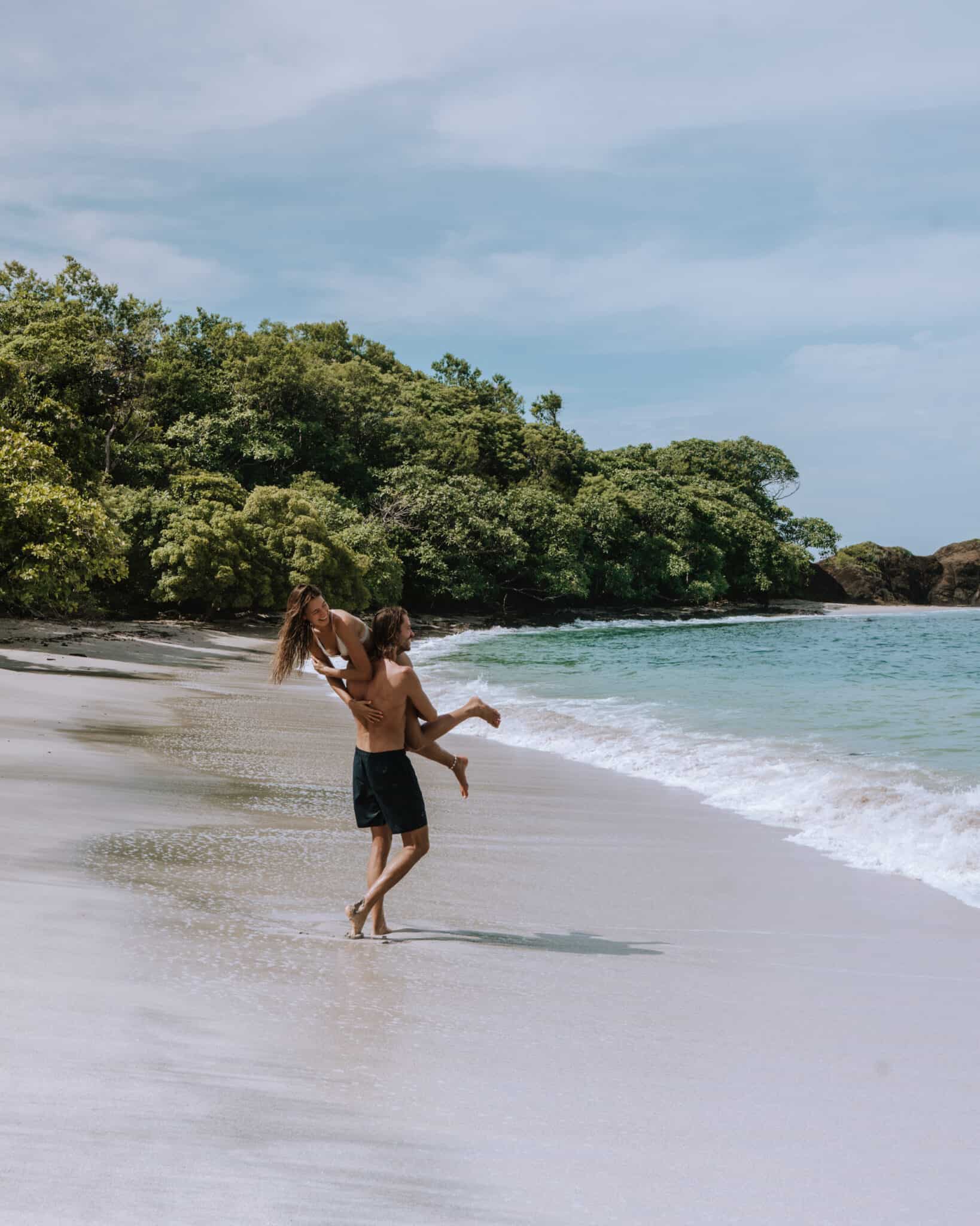 A couple holding hands on a beach in Nosara, Costa Rica.