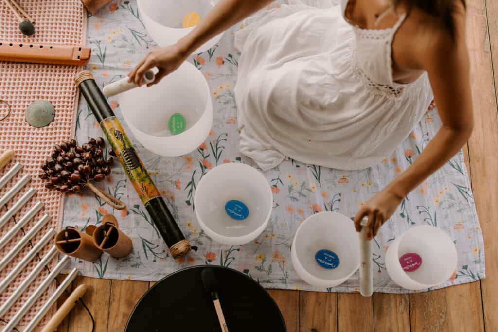 A woman is sitting on a wooden floor with bowls and musical instruments in Nosara, Costa Rica.