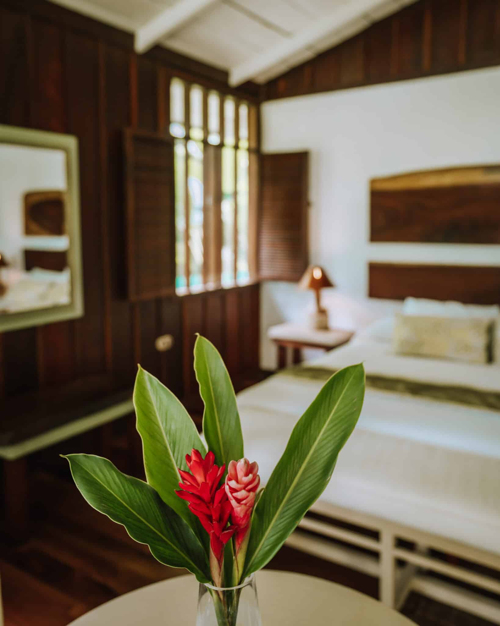 A bed in a room with a flower in a vase in Tortuguero, Costa Rica.