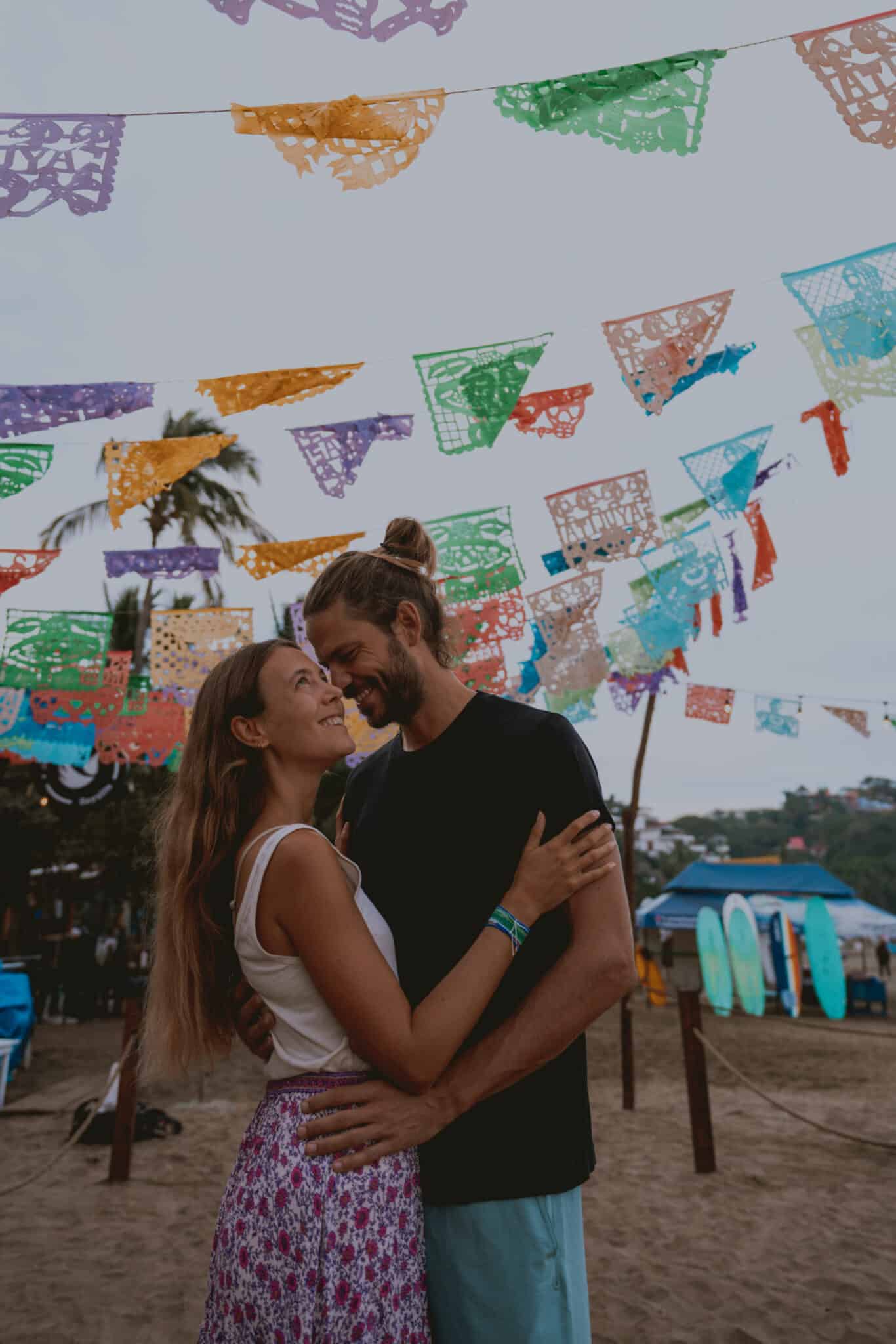 A couple embracing under colorful flags on the Sayulita beach.