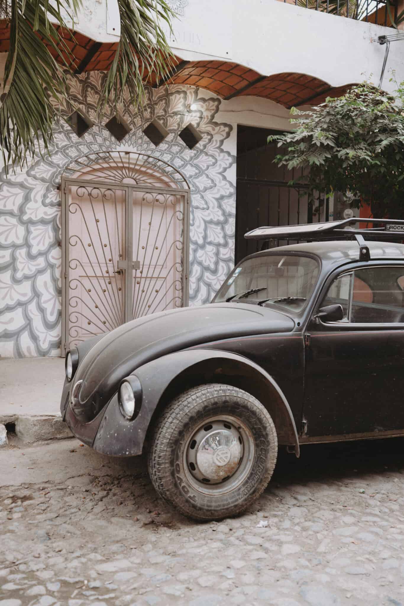 A black Volkswagen Beetle parked in front of a house in Sayulita.