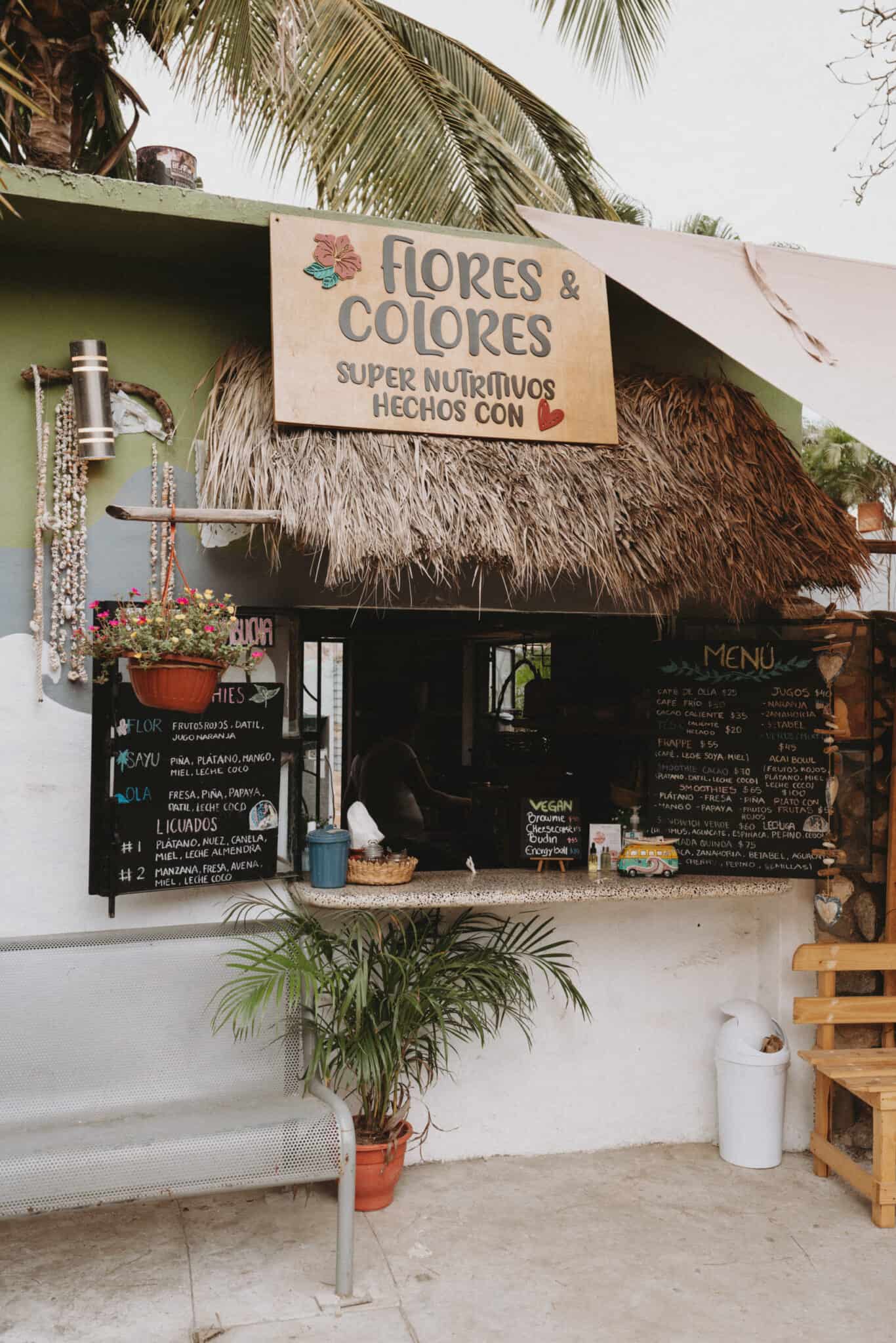 A Sayulita restaurant with a thatched roof in front of a palm tree.