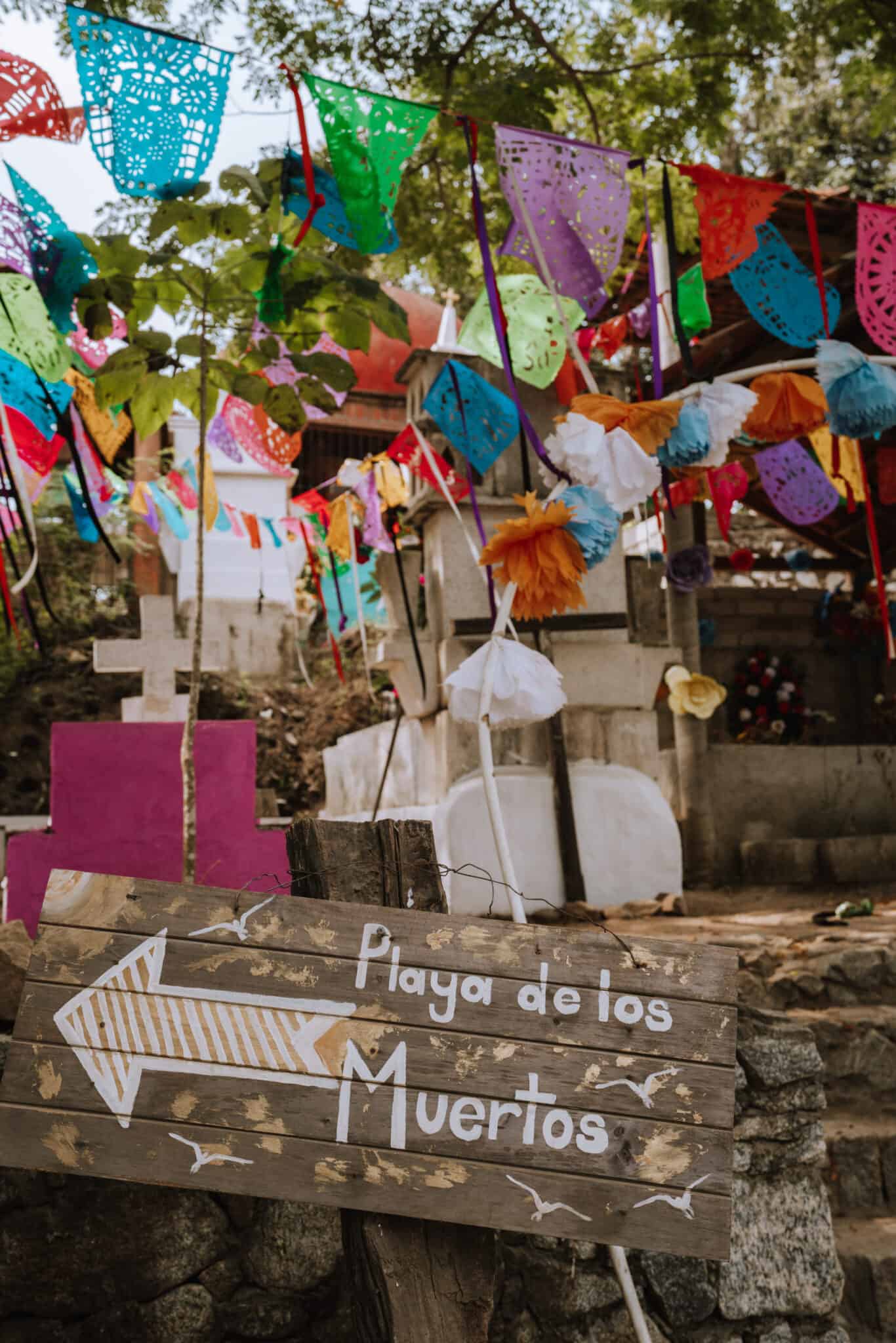 A Sayulita sign adorned with colorful flags.