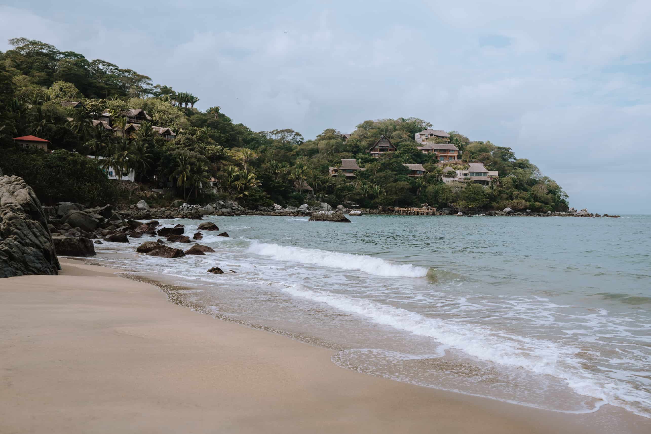 A rocky Sayulita beach with trees in the background.