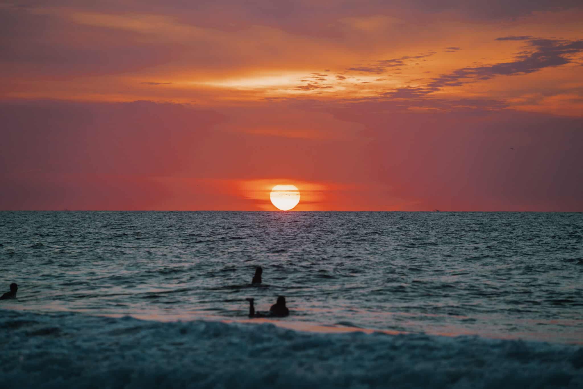 The sun is setting over a group of people in the ocean near Sayulita.