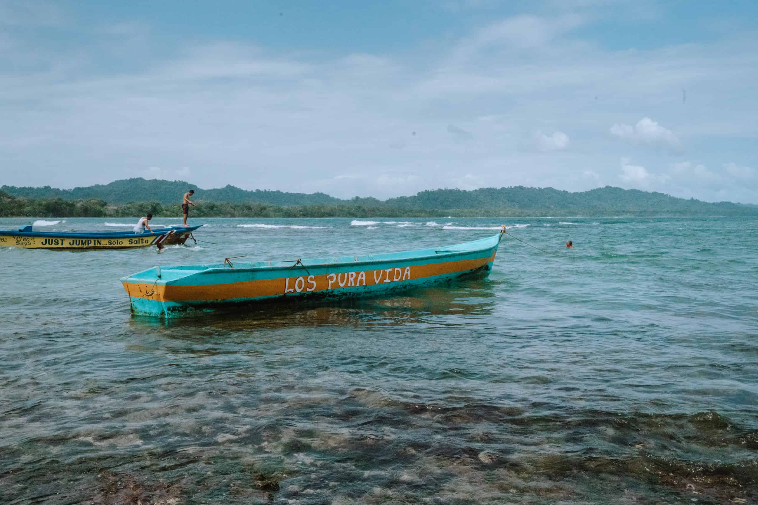 Two boats docked in the water near a beach in Puerto Viejo, Costa Rica.