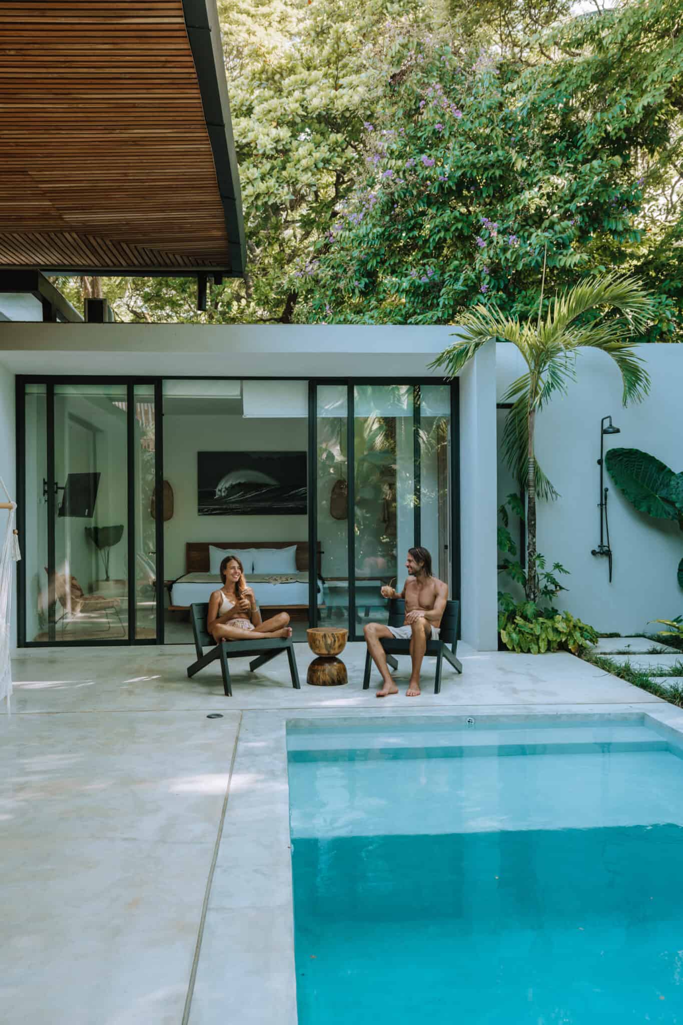 Two people work with us by a pool in a modern house.