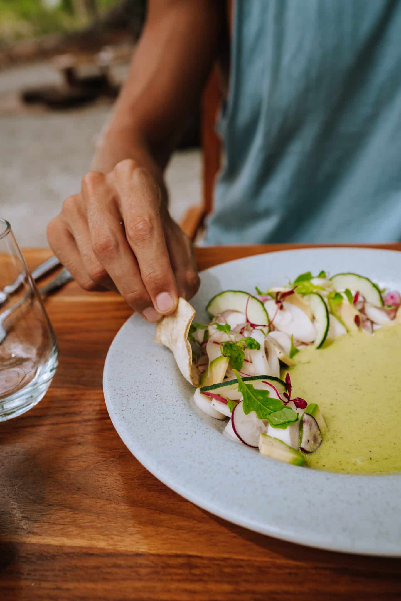 A man is enjoying a plate of food on a wooden table.