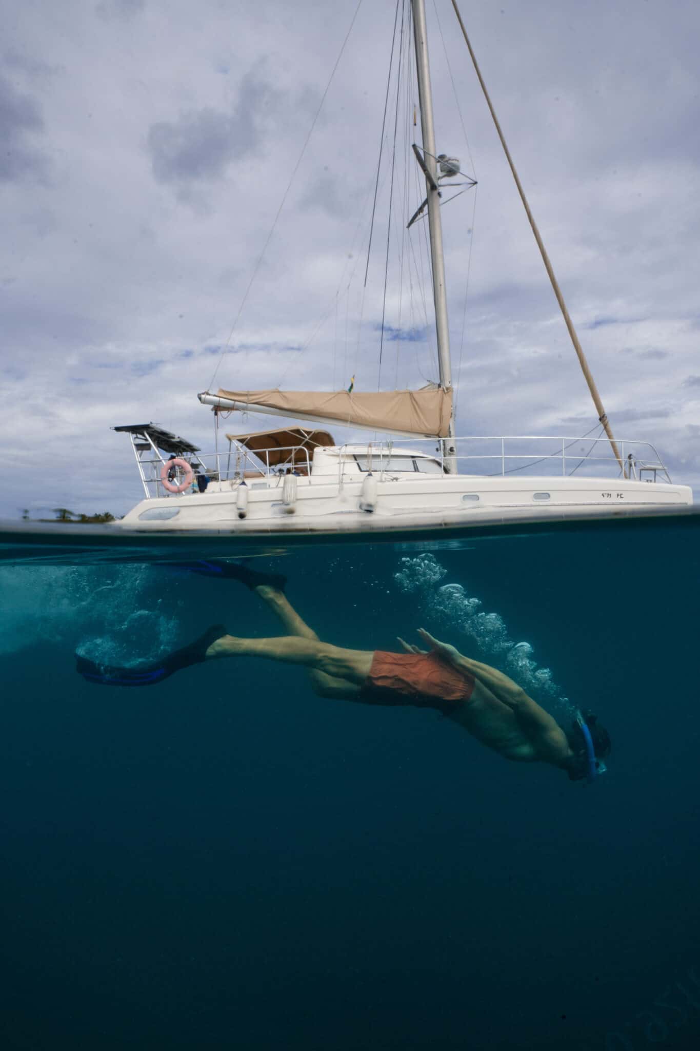 A man snorkels near a catamaran while working with us.