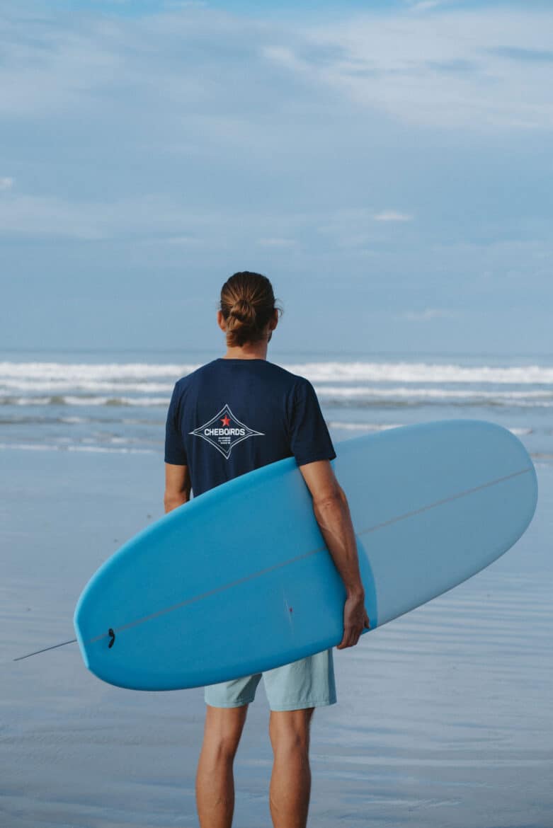 Man wearing shirt and carrying surfboard from cheboards at Playa Hermosa Costa Rica