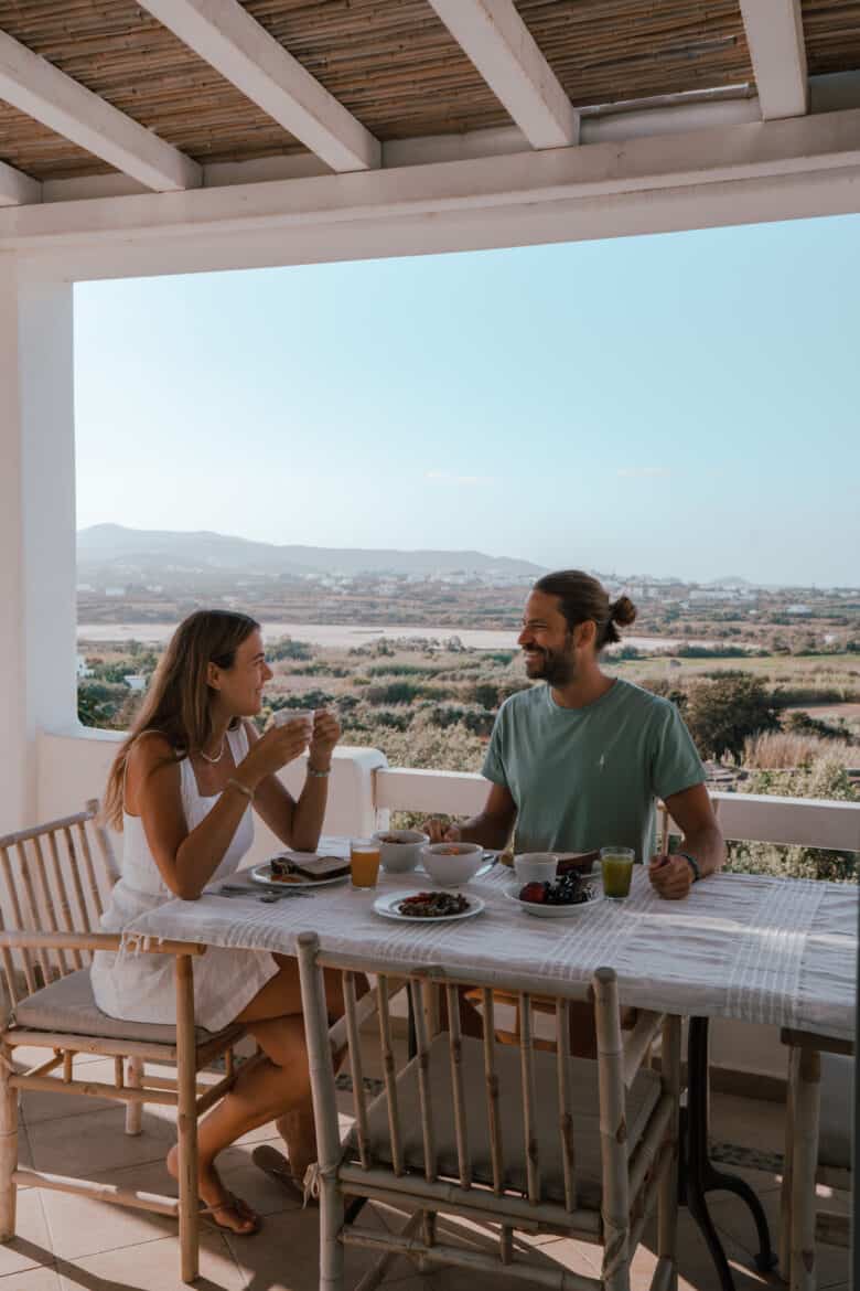 A couple enjoying breakfast on a Naxos Island balcony with a sea view.