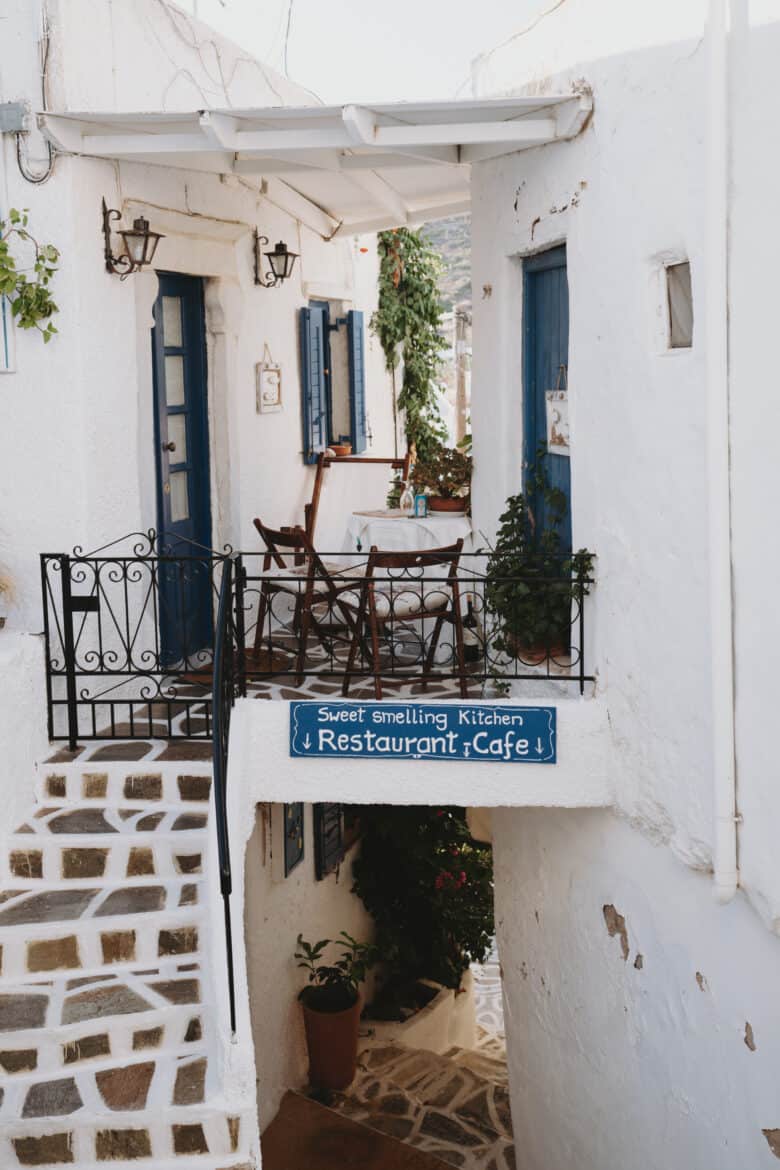 A white building with stairs and a blue door located on Paros Island.