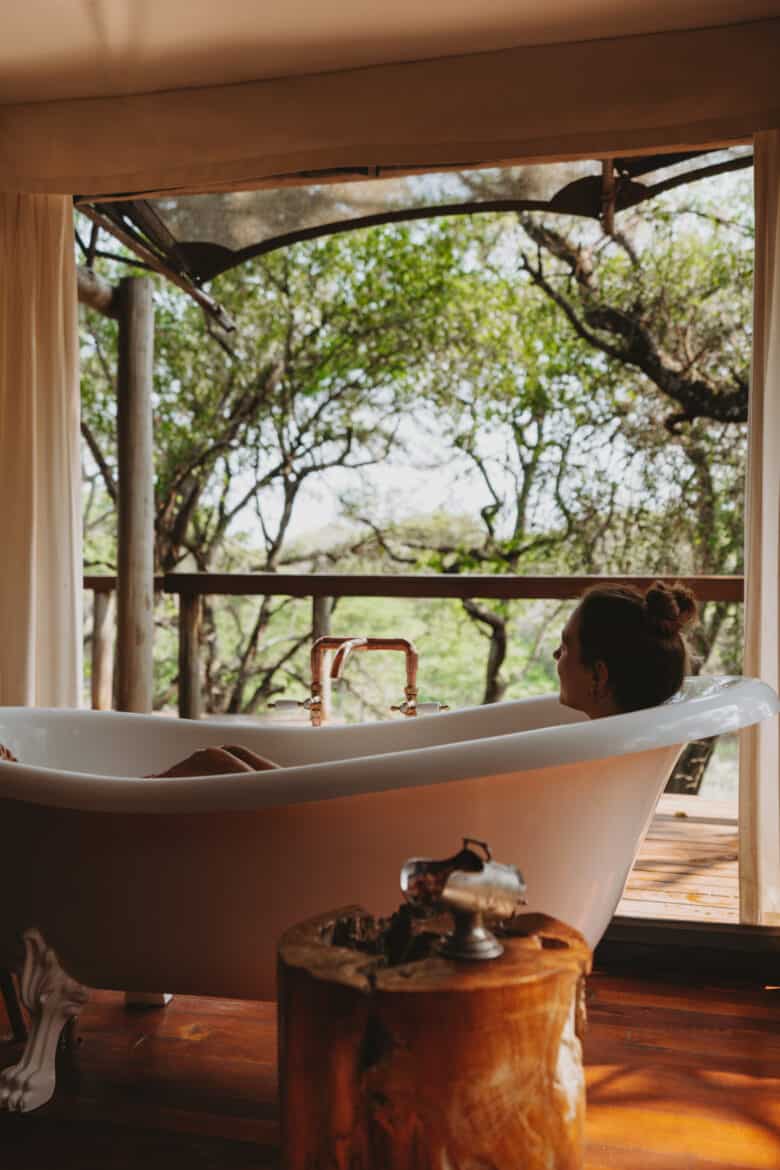 A woman enjoys a relaxing bath with a captivating view at Rhino Sands, South Africa.