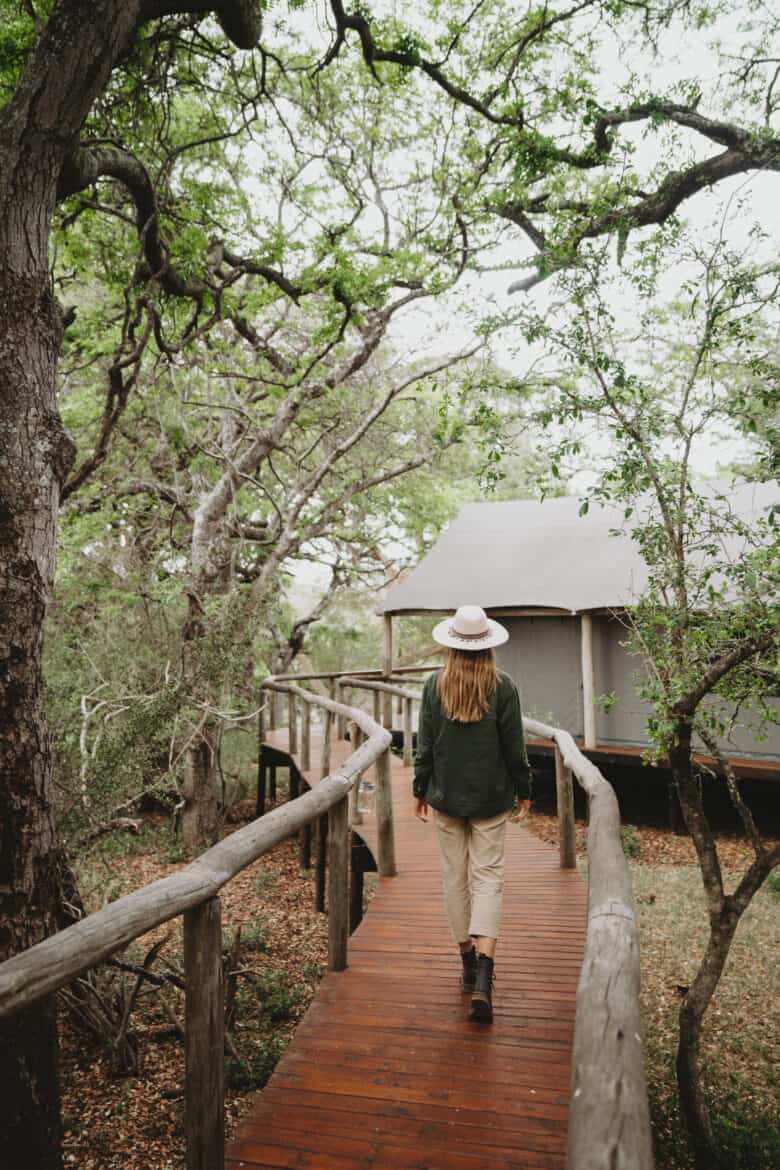 A woman walks down a wooden walkway to a lodge in South Africa.