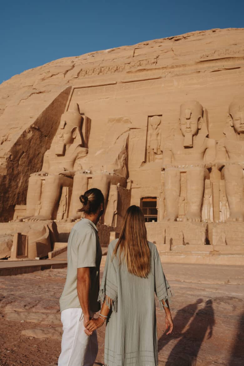 Couple holding hands in front of sphinxes on their Egypt itinerary.