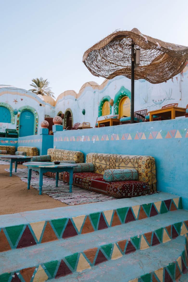 A blue painted building with couches and chairs in the sand, perfect for your Egypt itinerary.