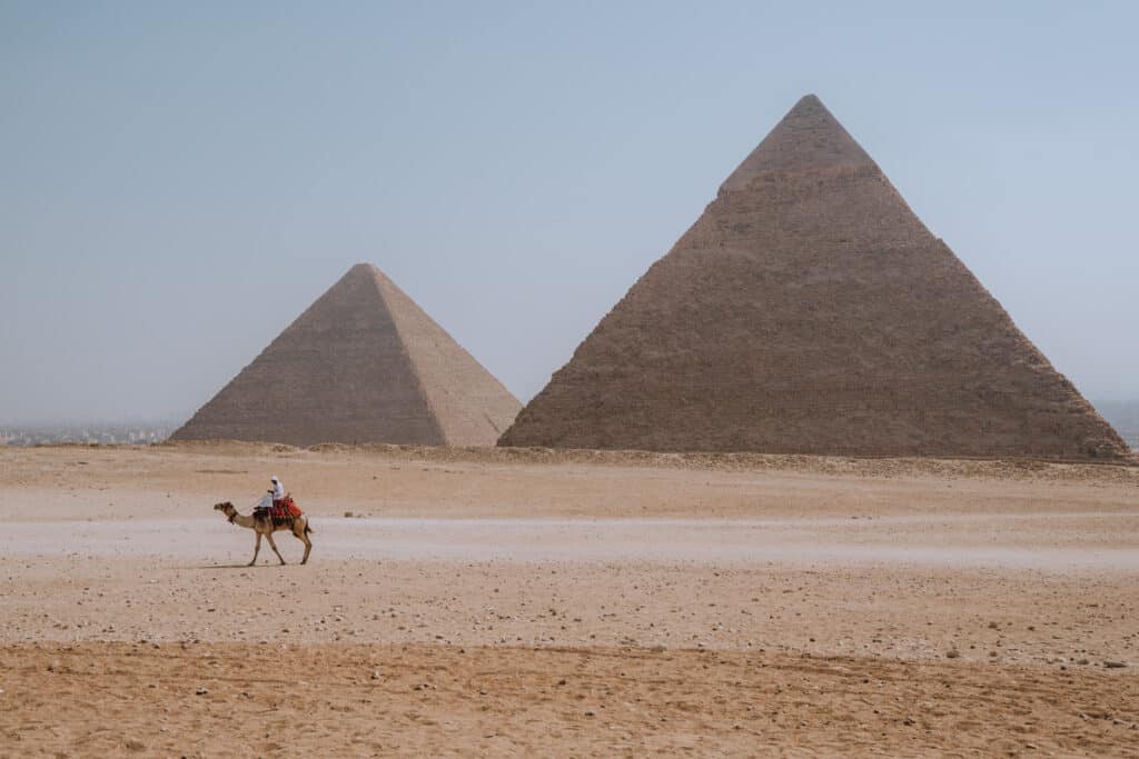 Man riding camel in front of pyramids at Giza, Egypt.