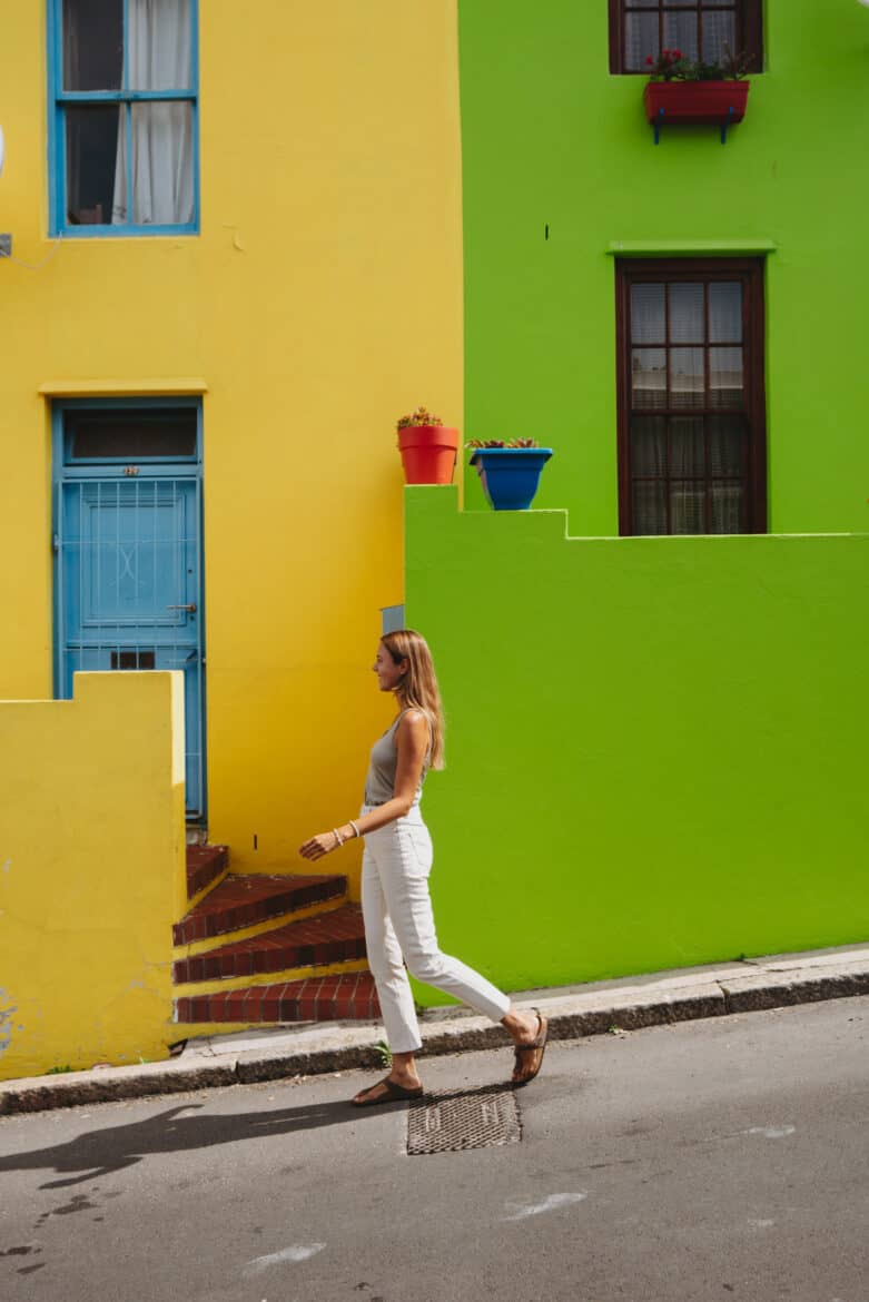 A woman walking past colorful houses in cape town.