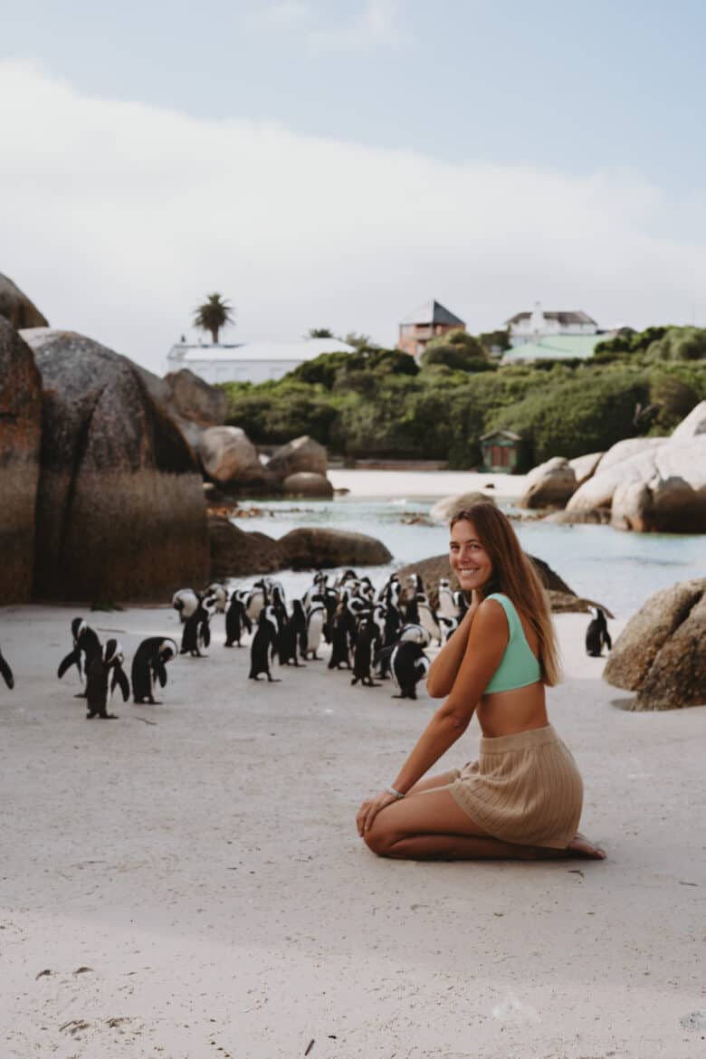 A woman enjoying Cape Town's beach surrounded by playful penguins.