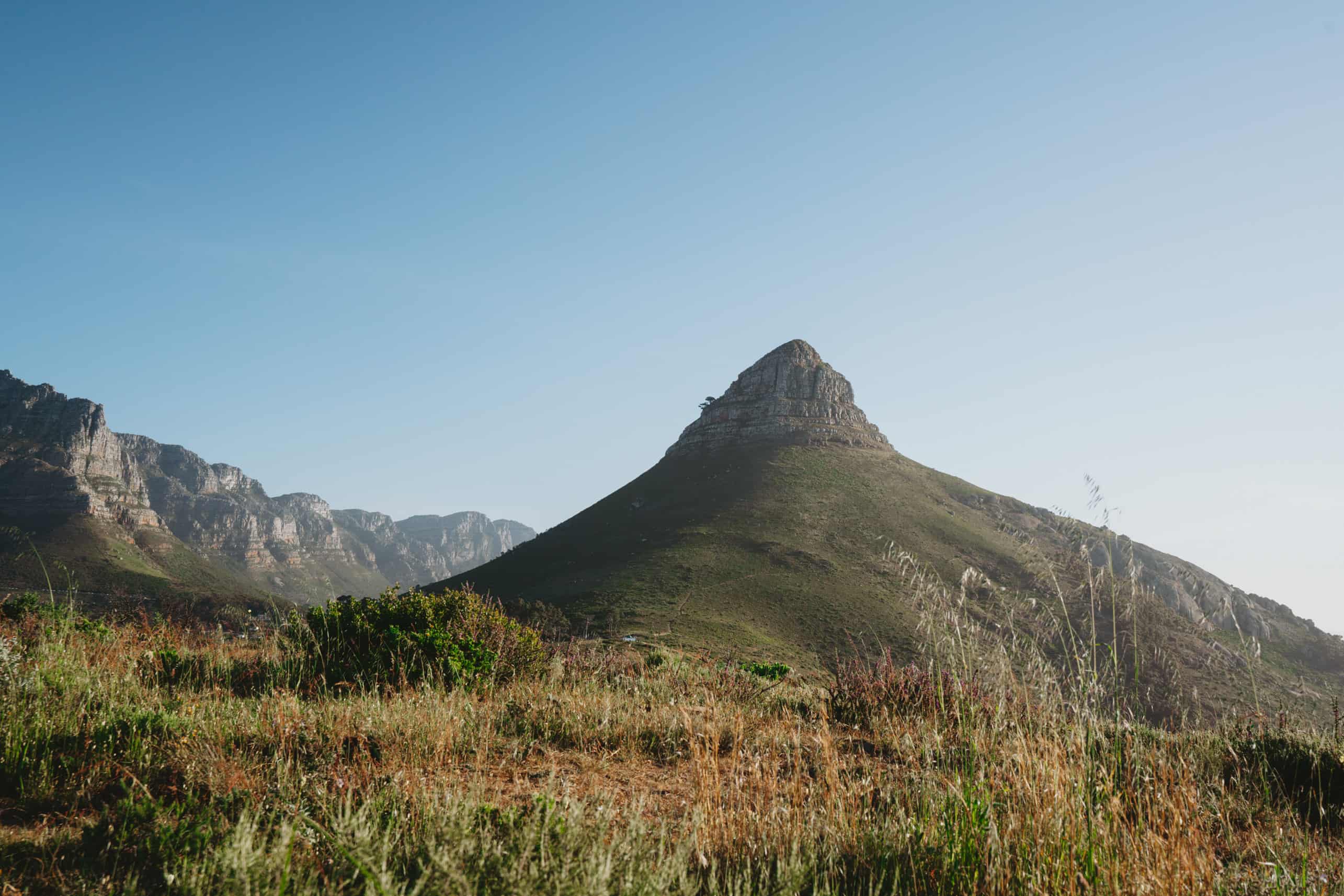 A scenic mountain range in Cape Town, South Africa, with lush grass and bushes in the background.