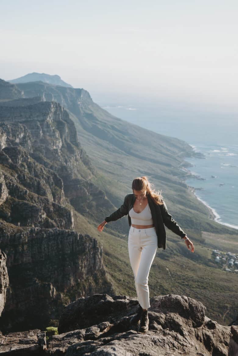 A woman standing on top of a mountain with her arms outstretched.