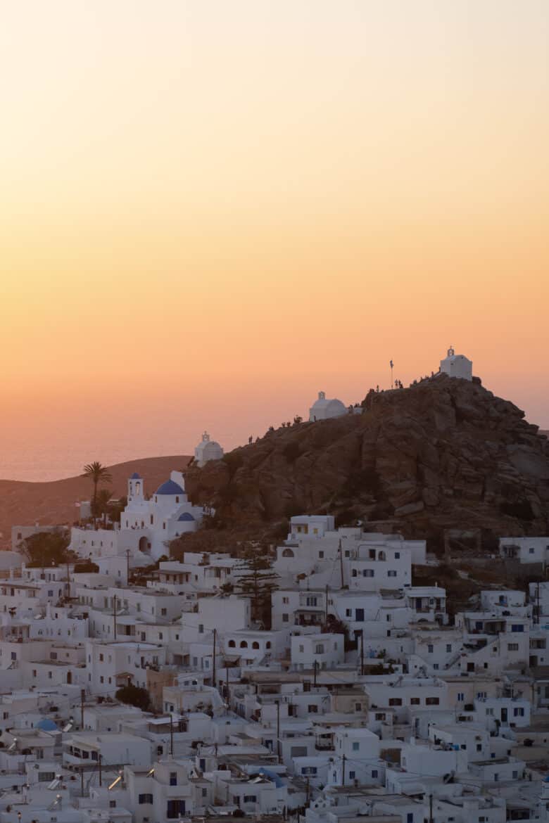 A picturesque view of a white town at sunset on the island of Ios, Greece.