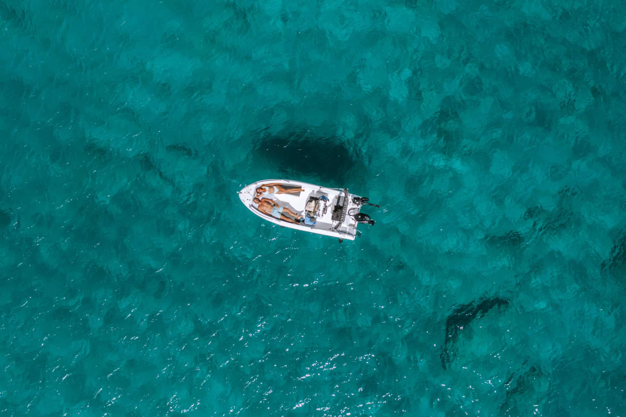 An aerial view of a small boat off the coast of Milos island, Greece.