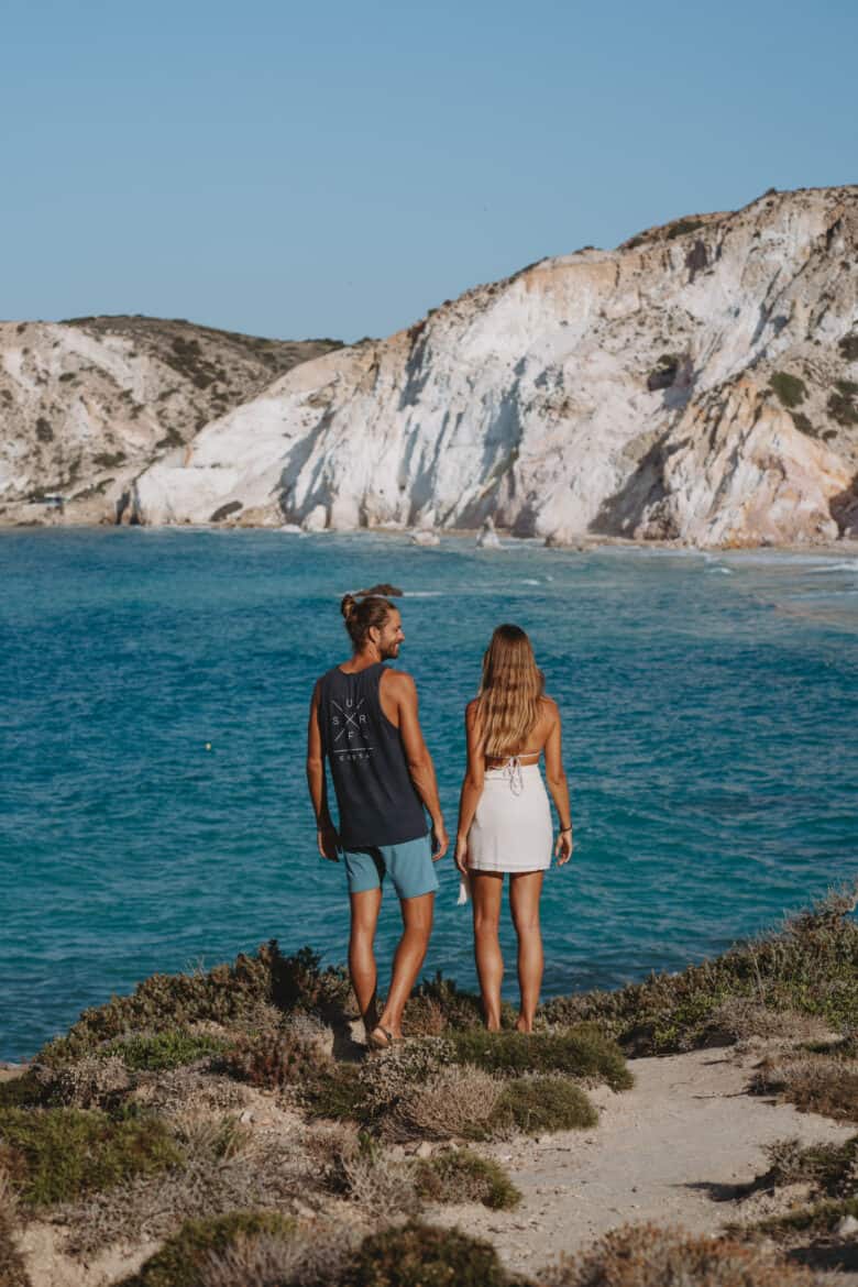 A couple standing on a cliff in Milos, Greece overlooking the ocean.