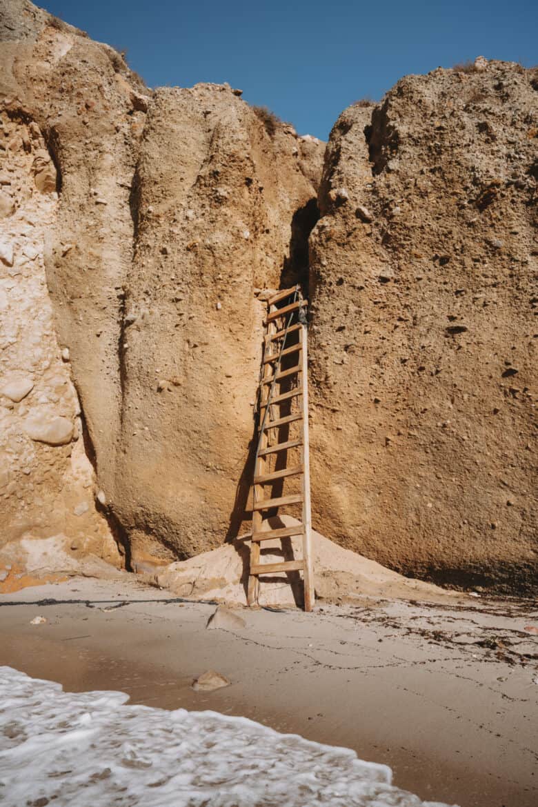 A wooden ladder leading up to a cliff on Milos Island in Greece.