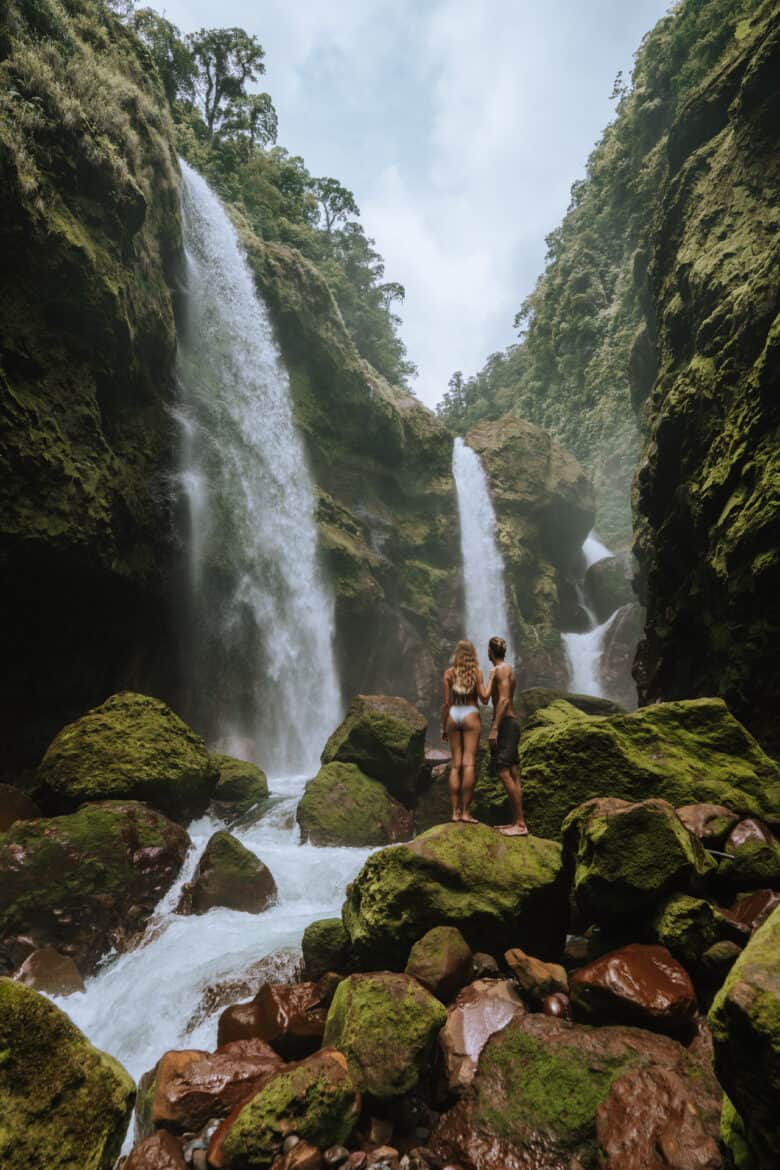 Two people standing in front of a waterfall in Bajos del Toro, Costa Rica.