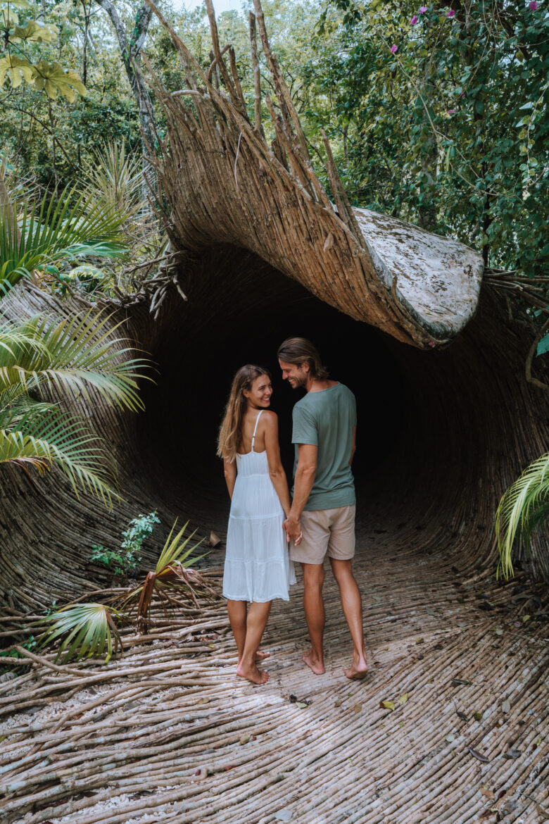 A couple standing in the middle of a tunnel in the jungle.