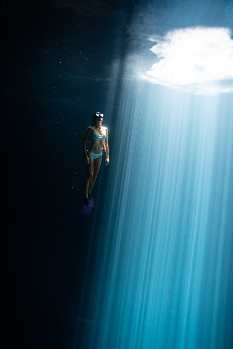 A woman is swimming in the water under a bright light.