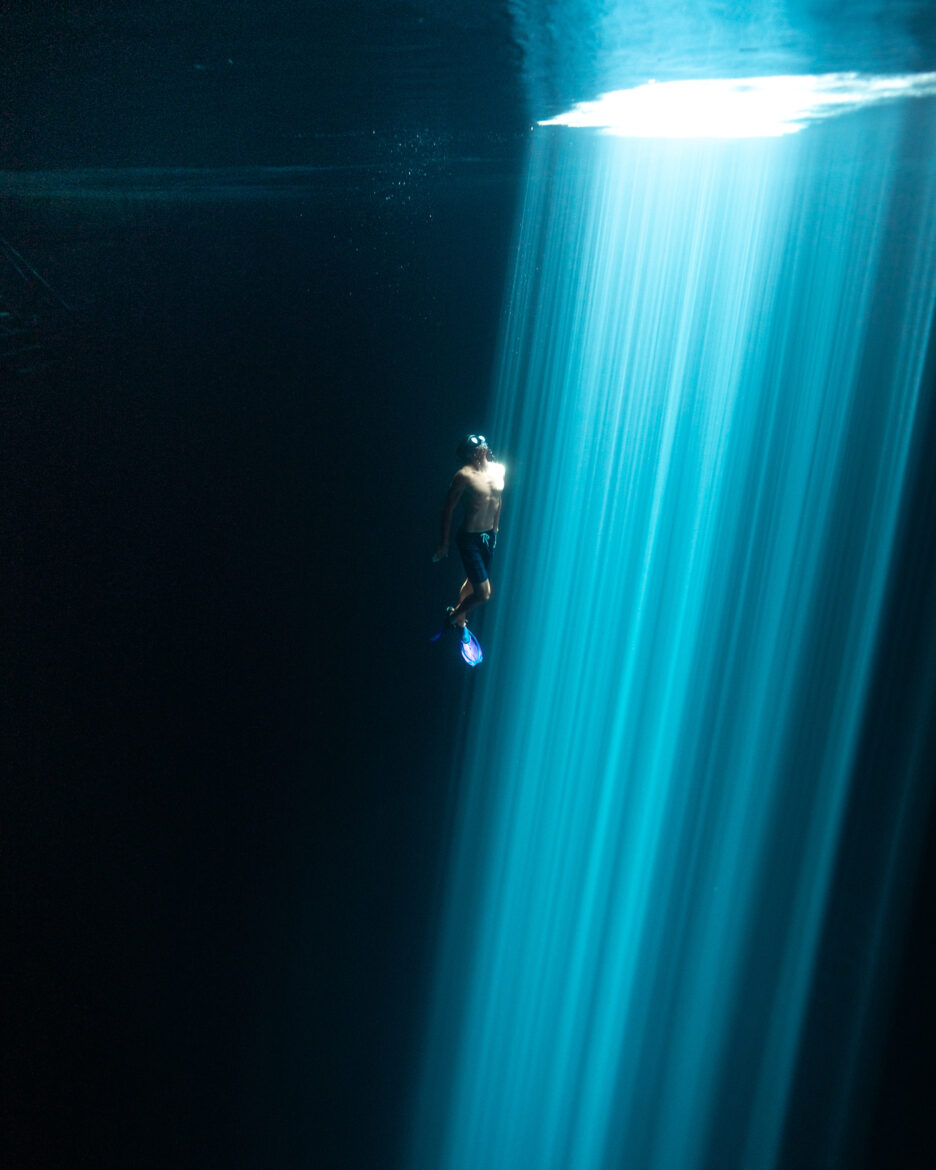 A man is swimming under a bright light.