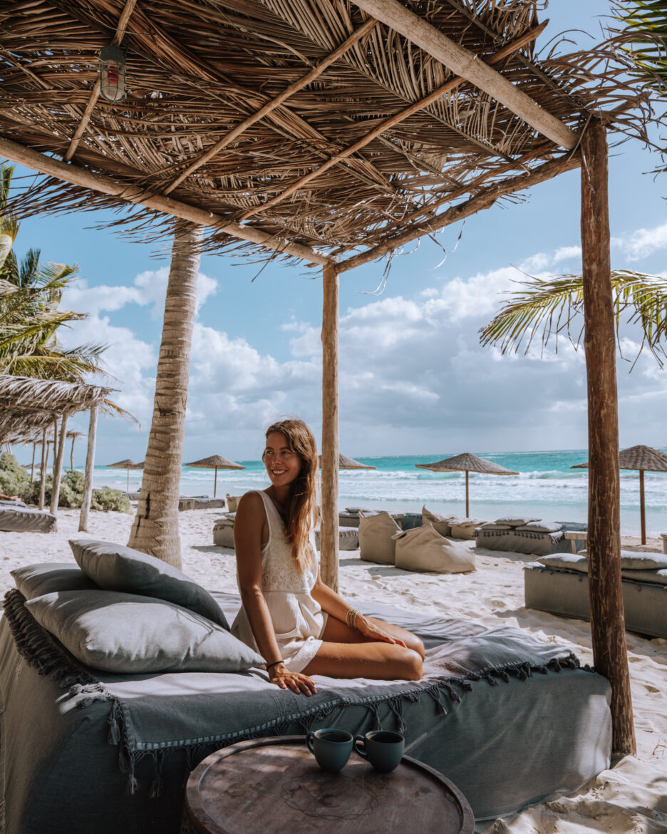 A woman sitting on a bed on the beach.