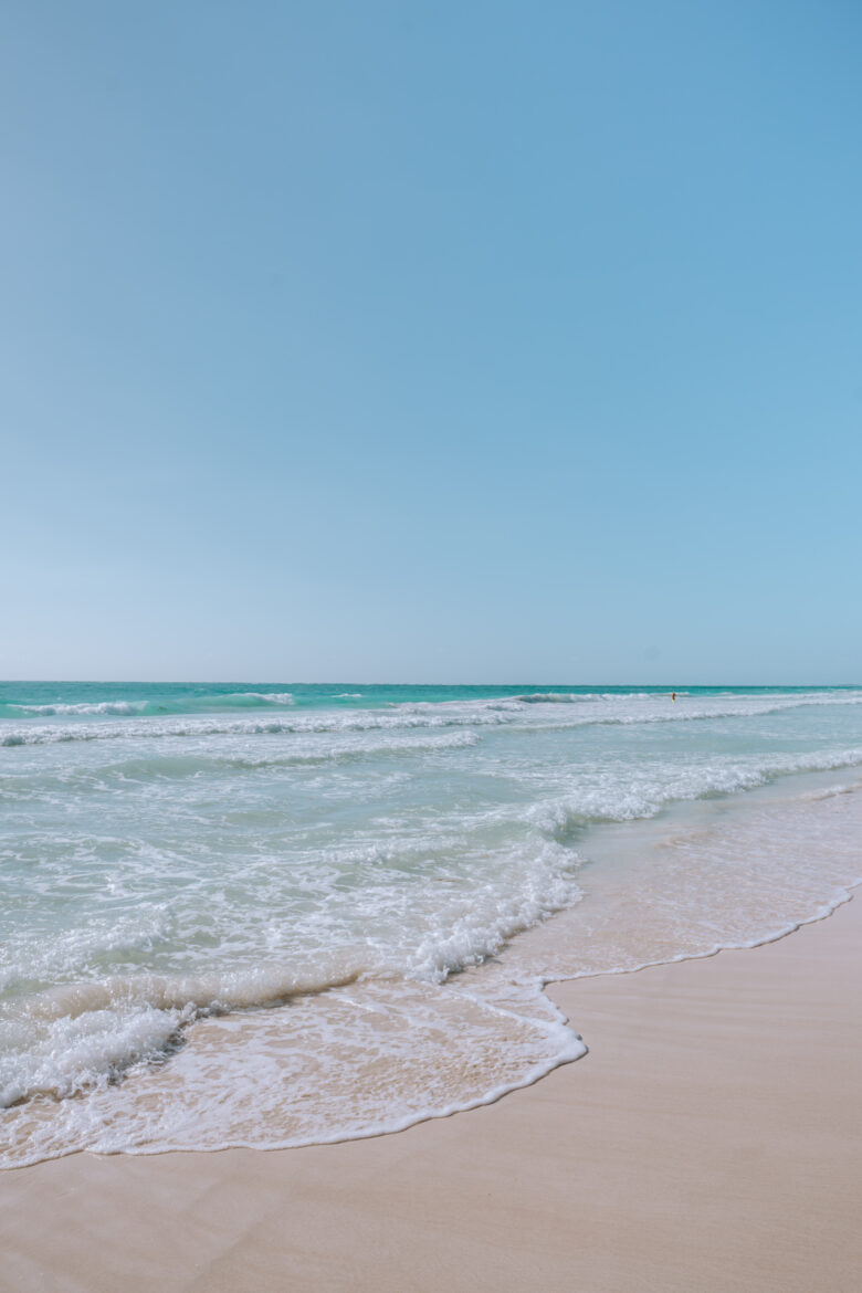A man is standing on a sandy beach.