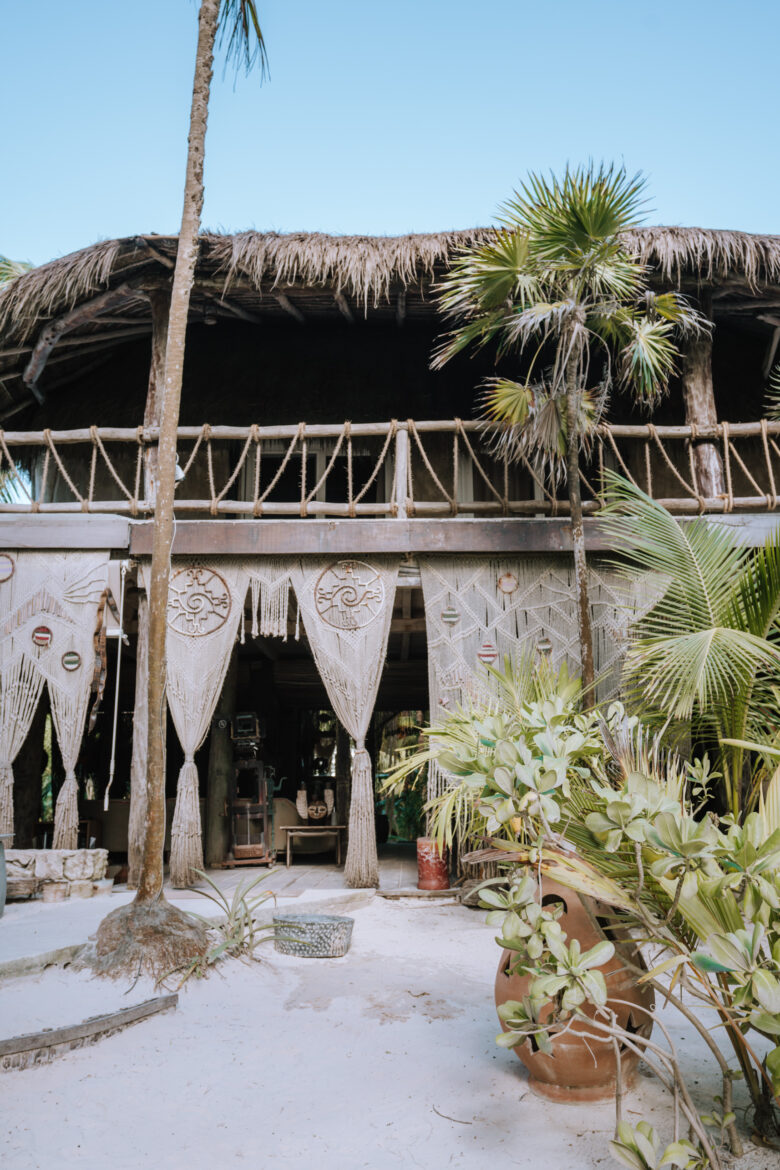 A house with a thatched roof and palm trees.