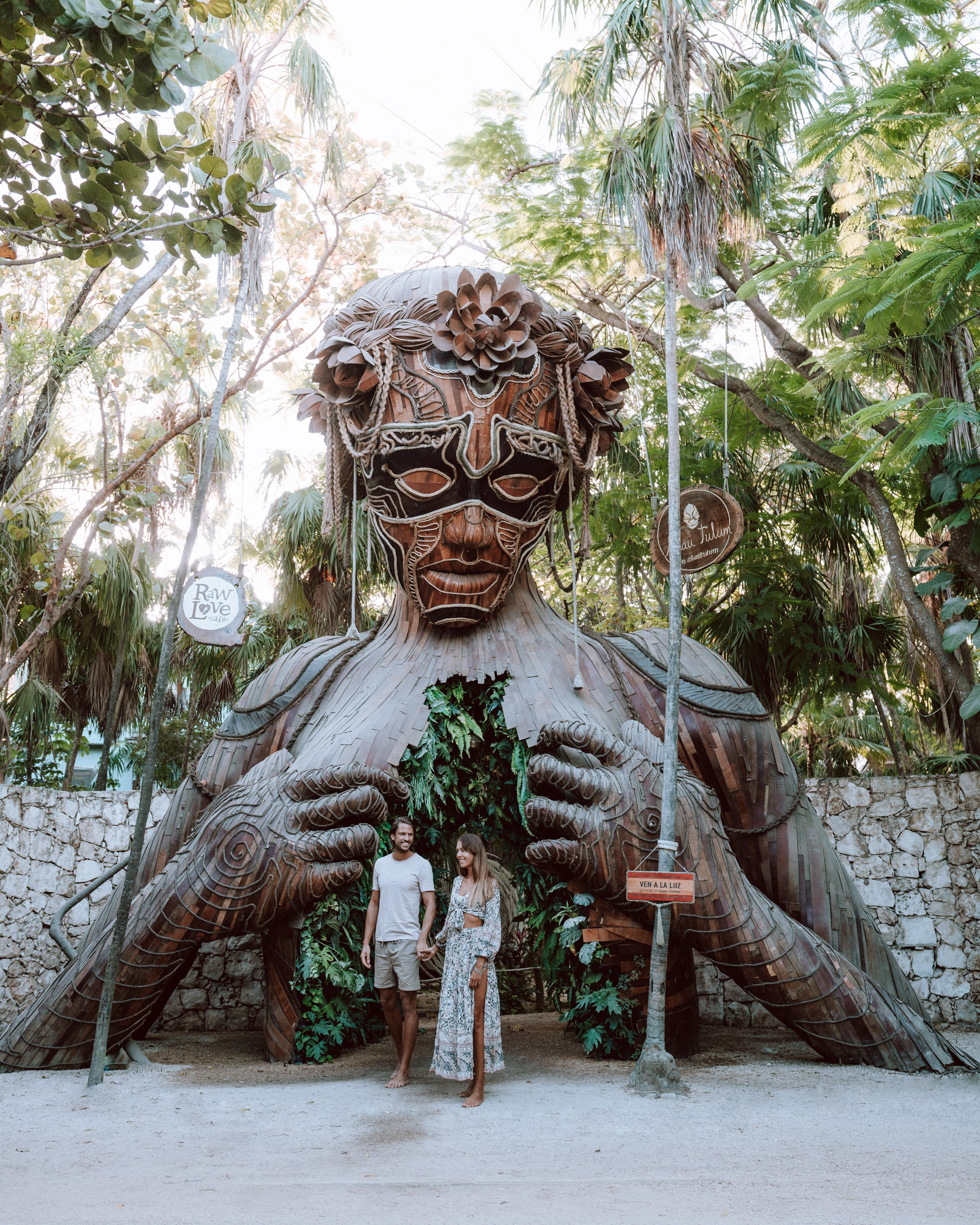 A couple standing in front of a statue of a woman, enjoying one of the best things to do in Tulum.